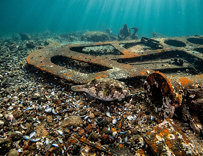 Underwater view of a concreted metal fitting on the rocky seabed, thought to be
                    the exit of the sternpost tube casing.