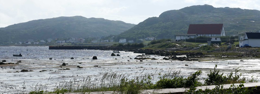 Low tide in the cove at Bonne-Espérance, a long wharf reaching out from the shore
                  and small boats resting on the exposed flats.